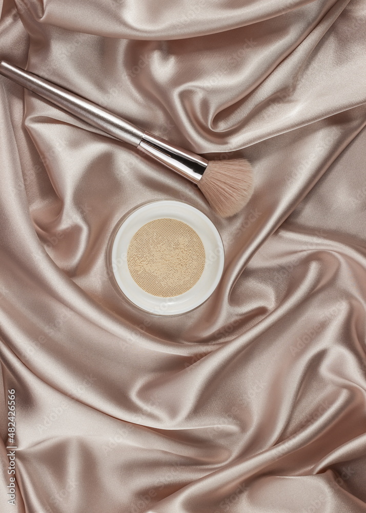 Fototapeta premium Face powder and brush,on a beige silk pastel background,make up,flat layot