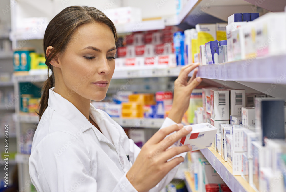 Finding just the right medication. Shot of an attractive young pharmacist checking stock in an aisle. Finding just the right medication. Shot of an attractive young pharmacist checking stock in an aisle.