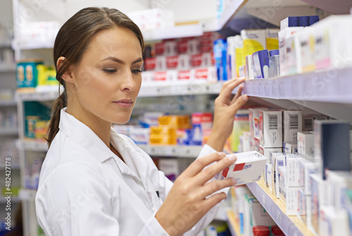 Finding just the right medication. Shot of an attractive young pharmacist checking stock in an aisle.