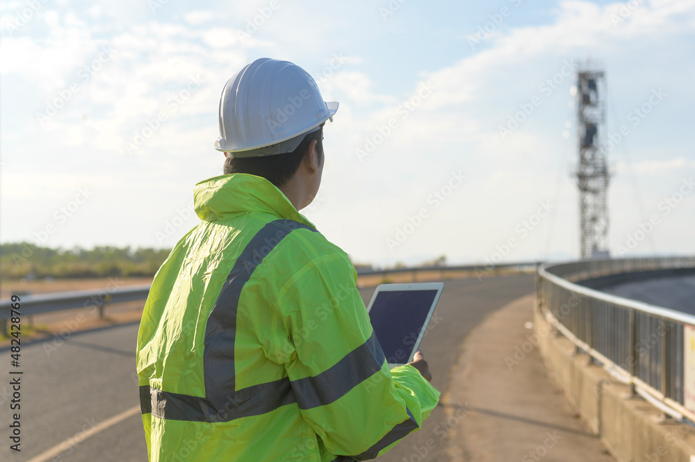 a man engineer is wearing a protective helmet on her head, using tablet Analytics engineering data... a man engineer is wearing a protective helmet on her head, using tablet Analytics engineering data...