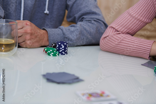 Man and woman hands in a poker game. Chips, cards, glass of whiskey on the table with reflection. Lifestyle photography. Poker club