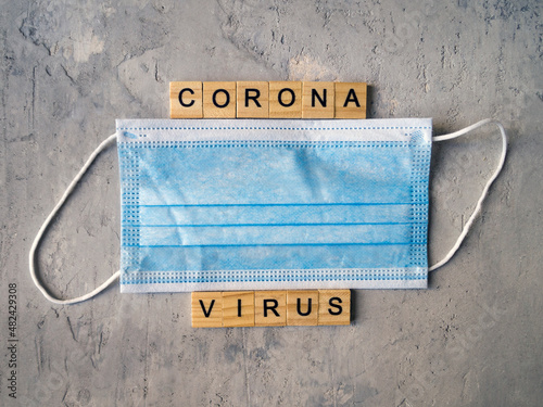 Words CORONA VIRUS lined with wooden letters on a background of blue surgical masks.