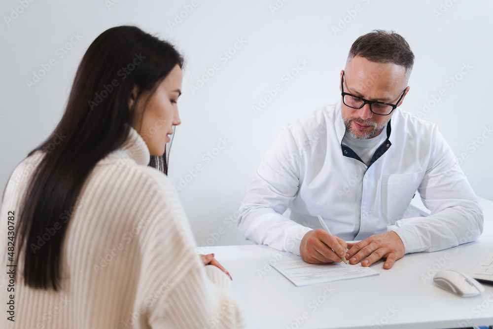 Male doctor writing a prescription for her patient Male doctor writing a prescription for her patient