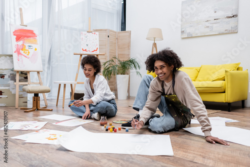 Cheerful young african american couple painting on floor at home. photo