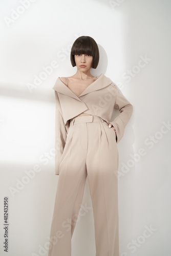 Beautiful brunette with graphic bob haircut wear beige fashion pantsuit photo