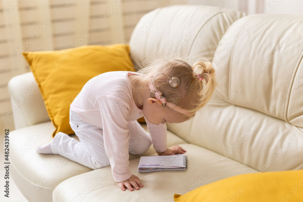 Baby with cochlear implants having fun at home. Deafness and medical technology concept.