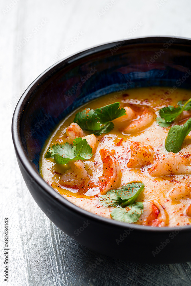 Tom Yam soup with shrimps on blue bowl on grey table