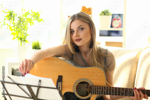Young woman is learning to play guitar closeup