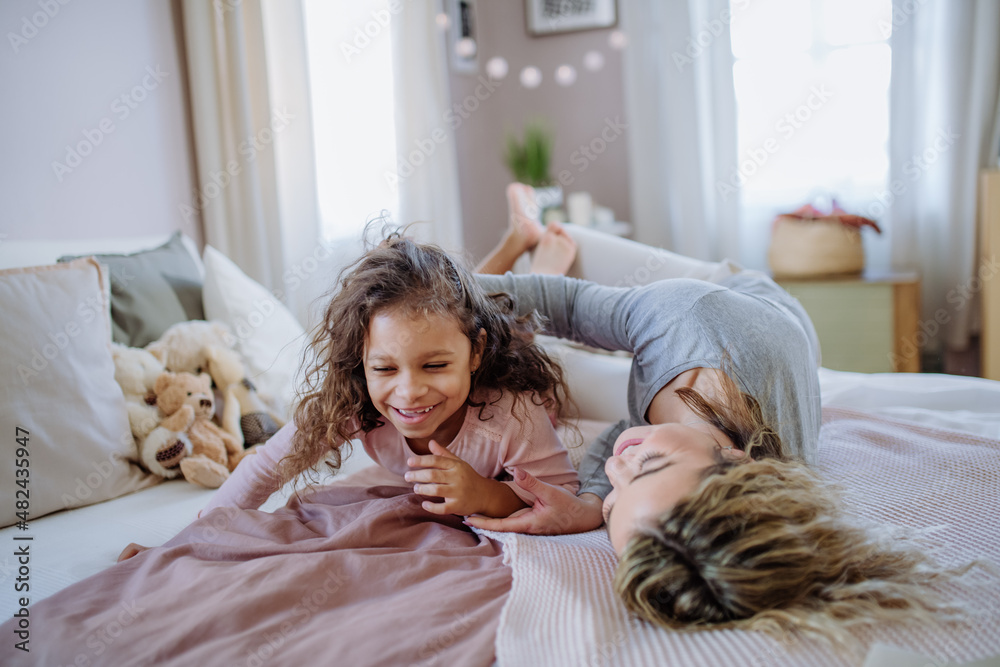 Happy mother with her little daughter hugging and having fun together on bed at home. Happy mother with her little daughter hugging and having fun together on bed at home.