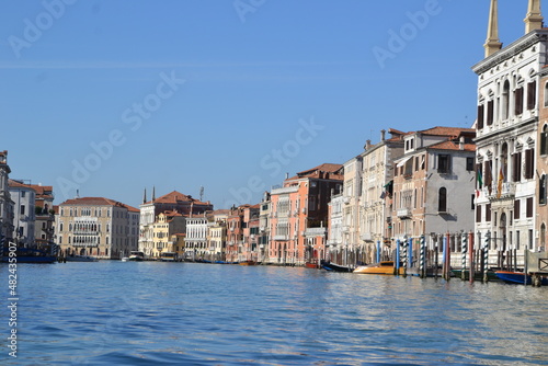 canal in venice, italy, with old buildings on the side, in a gondola ride, in blue tones, in the blue sky, reflection in the water