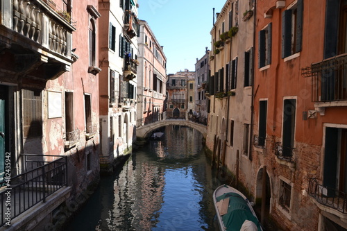 canals of venice  italy  with old buildings on the side  in a gondola ride  in red tones  in the blue sky  reflection in the water
