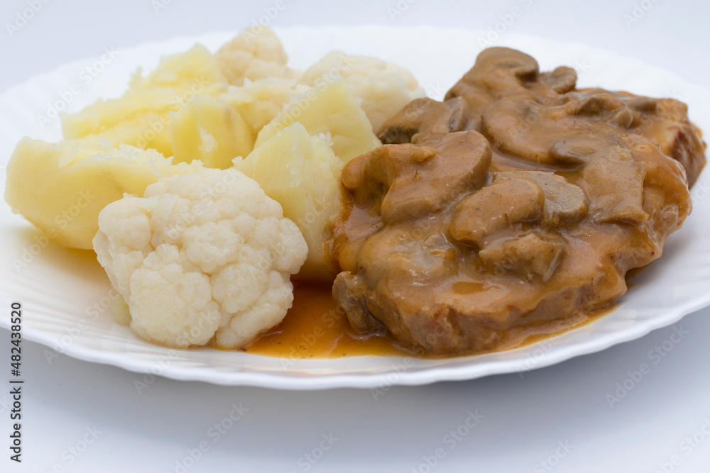 A meat dish with mushroom sauce, accompanied by potatoes with cauliflower. Delicious food concept. A meat dish with mushroom sauce, accompanied by potatoes with cauliflower. Delicious food concept.