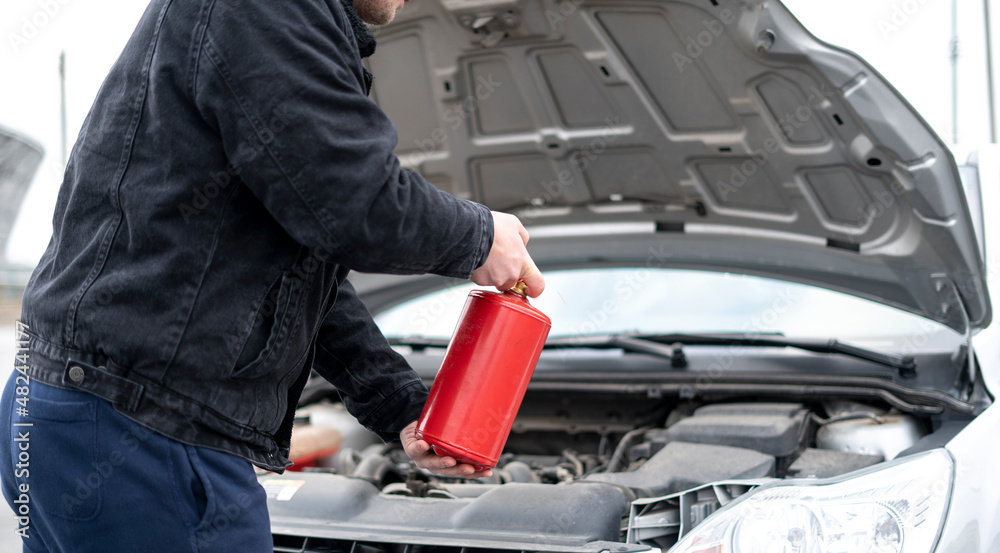 male driver holding red fire extinguisher near the to prevent the car burning accident