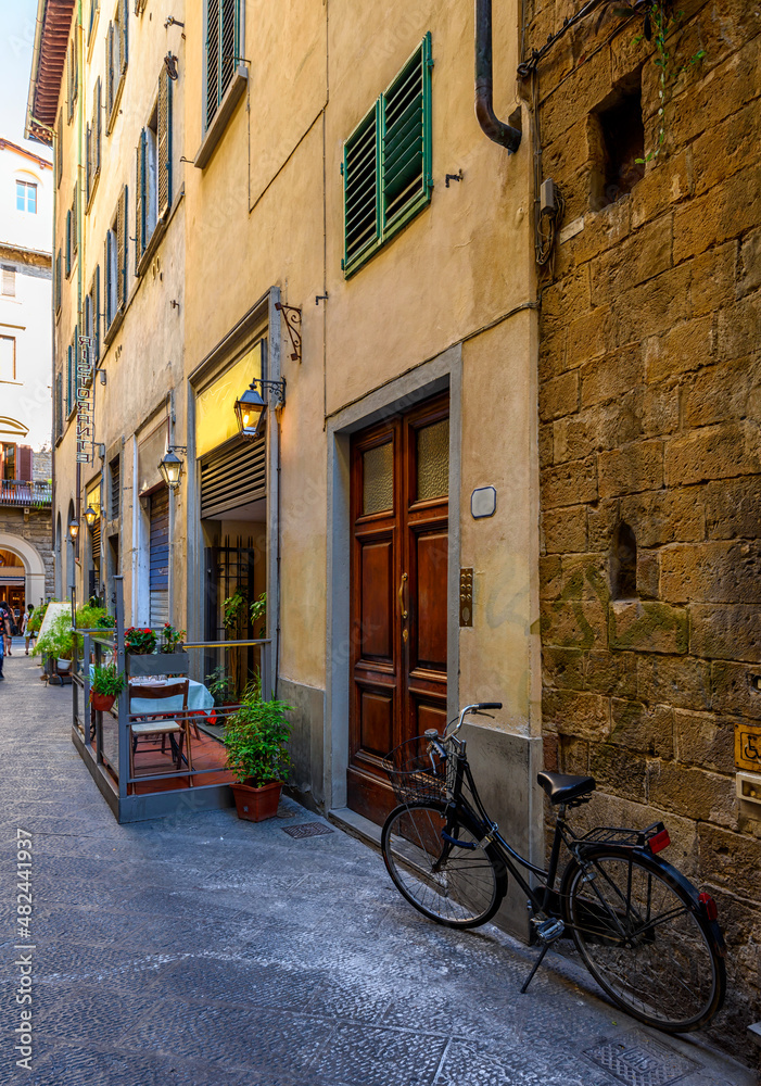 View of narrow street with tables of old trattoria in Florence, Tuscany, Italy. Architecture and landmark of Florence. Cityscape of Florence