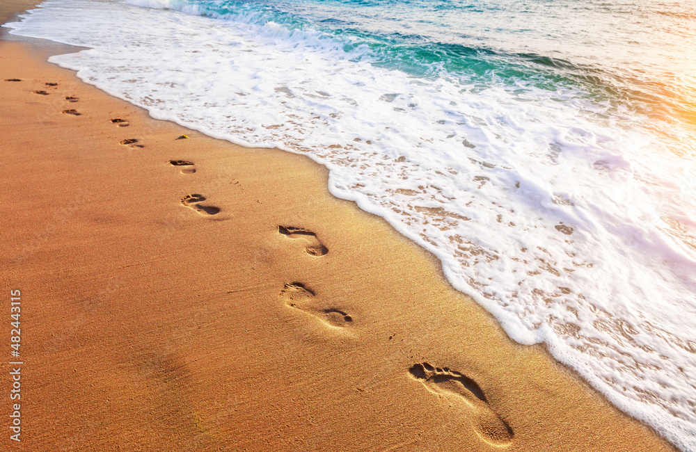 footprints on  tropical beach and beautiful  wave