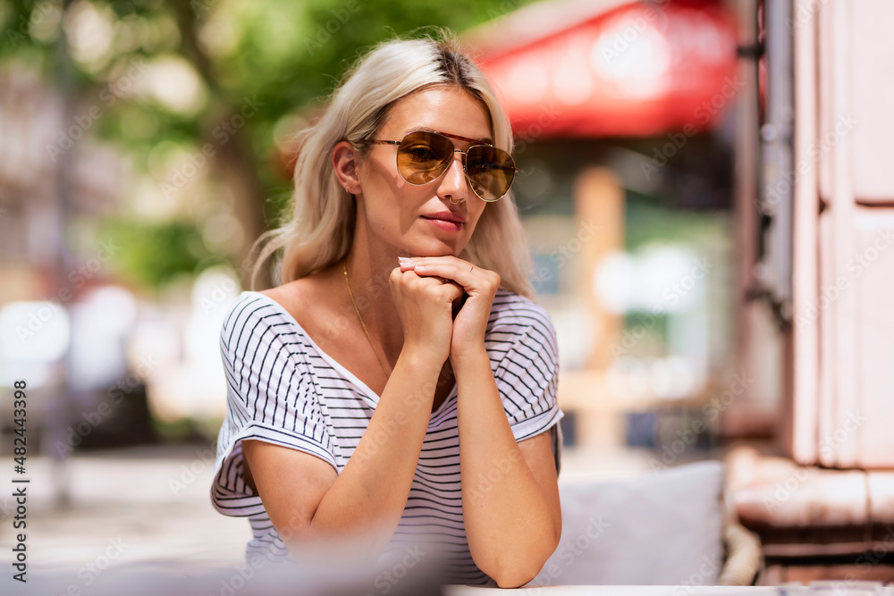 Fototapeta premium Portrait of attractive blond haired young woman sitting outdoor