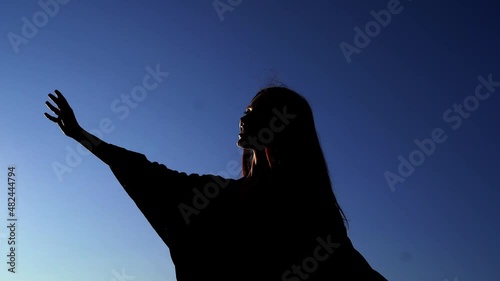 Silhouette girl dancing. Beautiful caucasian elegant girl in dress dancing during sunset or woman performing modern dance outdoor in sunny day against blue sky. High quality 4k video footage