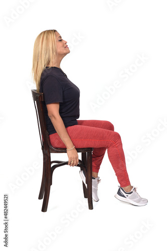 side view of a woman dressed in sportswear sitting on a chair on white background