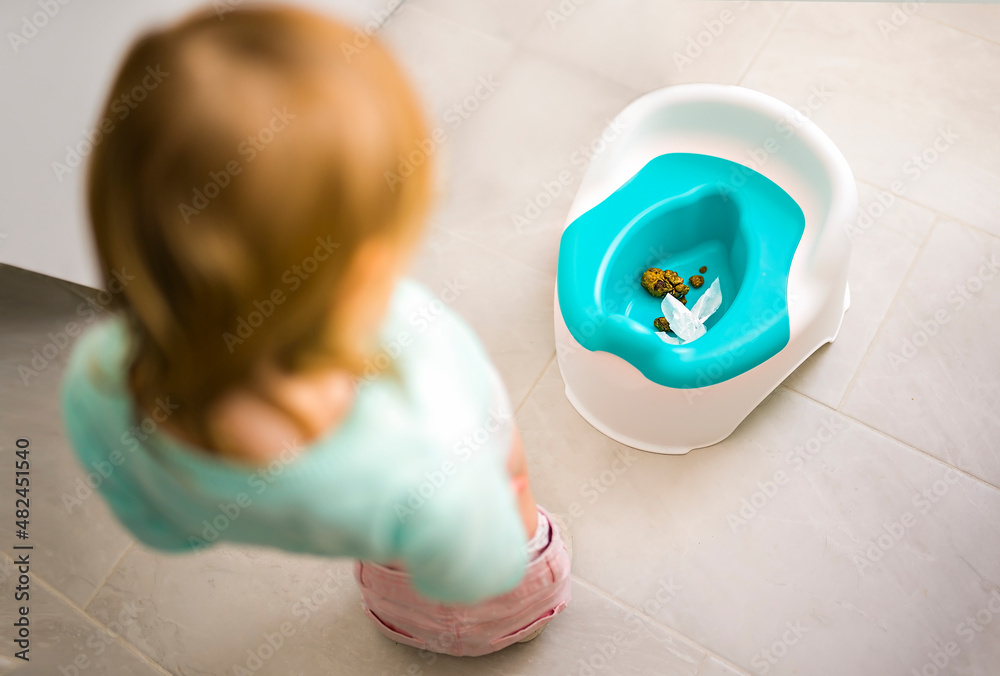 cute child girl is looking chamberpot poo on the bathroom