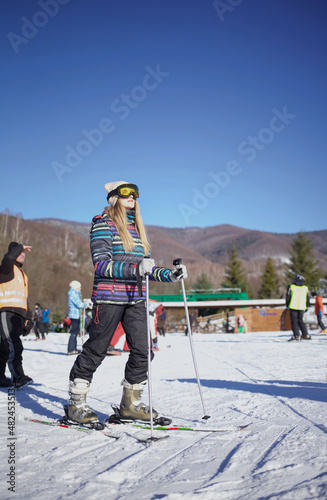 girl on skis looks up. there is snow on the street