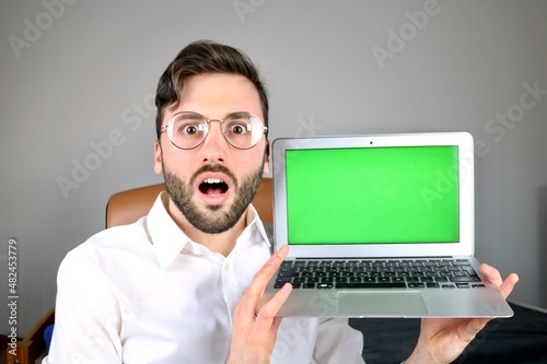 Fotografía Young surprised Computer scientist showing laptop with green screen display