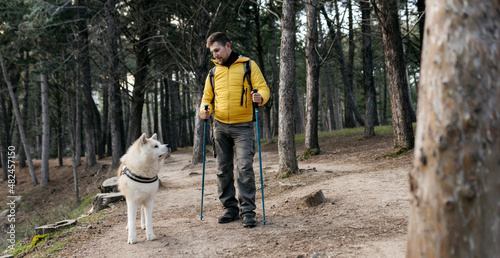 man trekking in the forest with his dog