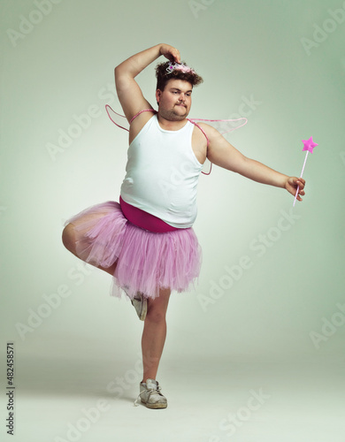 I do ballet. An overweight man comically dressed-up in a pink fairy costume doing ballet. photo