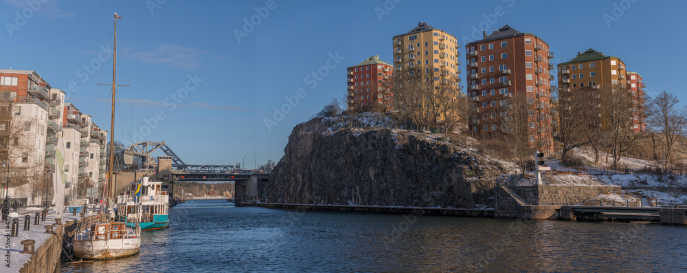 Panorama view of color full apartment tower houses on the hill Danviksklippan and apartments on the pier Hammarbyhamnen at the channel Danvikskanalen a snowy and sunny winter day in Stockholm