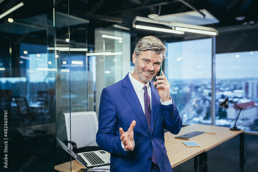 Successful boss working in a modern office, gray-haired businessman talking on the phone Successful boss working in a modern office, gray-haired businessman talking on the phone