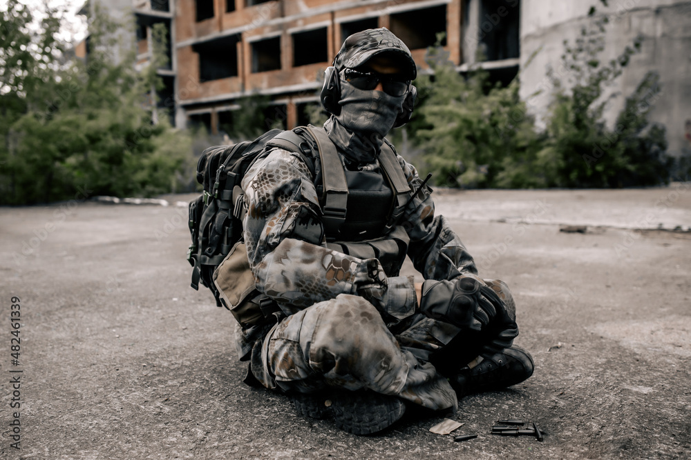 Fototapeta premium Soldier sitting on the ground with cartridges and a rifle