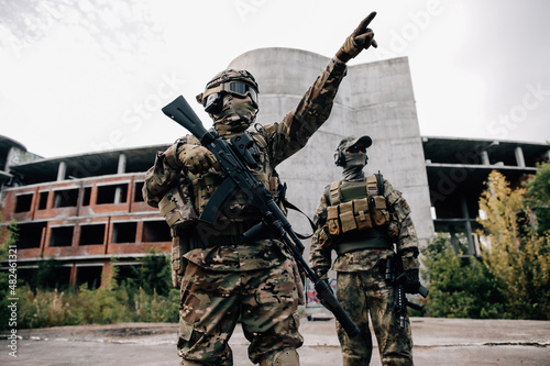 Two soldiers in camouflage uniforms with rifles in front of a building photo