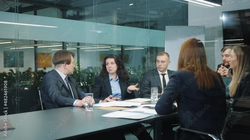 Business people in official wear sitting in office behind glass wall and discussing project, colleagues sharing ideas, teamwork of managers brainstorming, executives planning strategy, tracking shot Business people in official wear sitting in office behind glass wall and discussing project, colleagues sharing ideas, teamwork of managers brainstorming, executives planning strategy, tracking shot