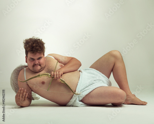 A whole lotta lovin'. An obese man relaxing while dressed like a cherub. photo