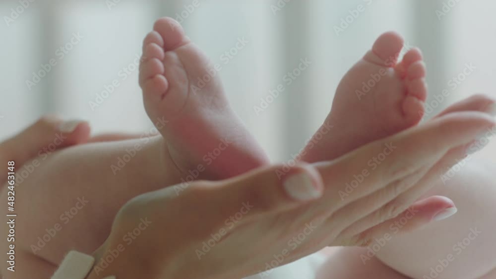 Pretty cute baby legs in the morning routine young mother touching carefully the little legs of her baby Pretty cute baby legs in the morning routine young mother touching carefully the little legs of her baby