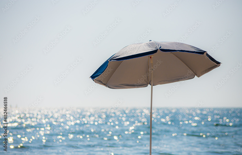 umbrella on a sandy beach with a cloudy sky, peaceful sea in background