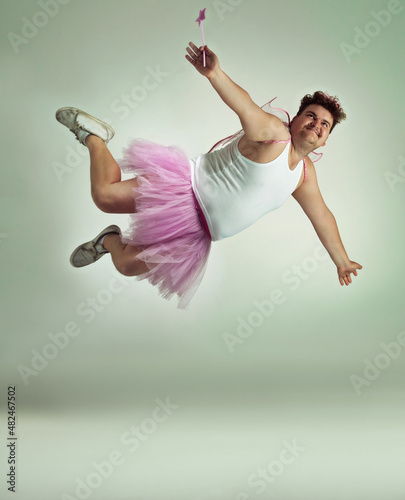 Let's fly away. A flying overweight man comically dressed-up in a pink fairy costume.