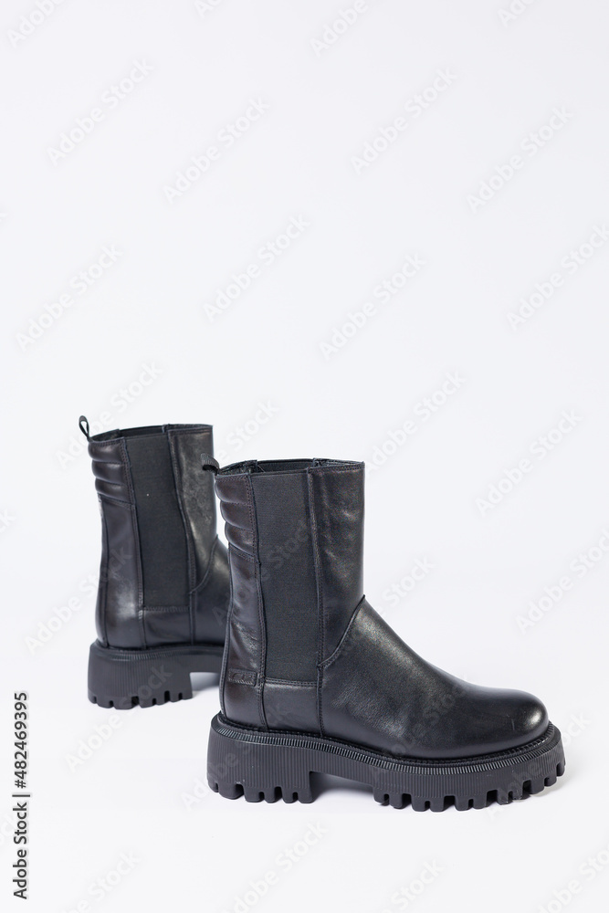 Women's shoes on a white background. Close-up of women's black leather chelsea boots on a white background. Shoes for the city. Fashion, design and footwear concept. Women's shoes on a white background. Close-up of women's black leather chelsea boots on a white background. Shoes for the city. Fashion, design and footwear concept.