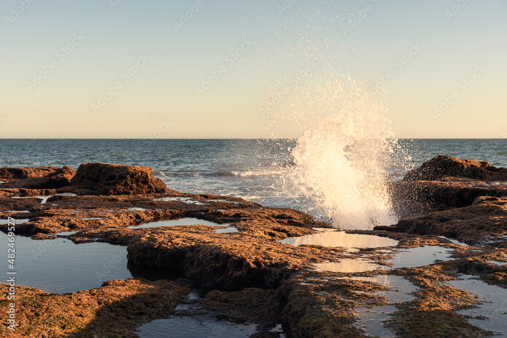 Waves crash over the rocks at Cadiz Bay at sunset, Andalusia, Spain