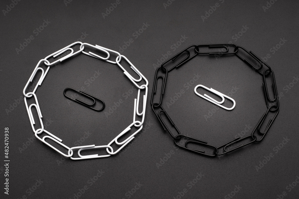 Black and white paper clips surrounded by opposite paper clips. Looped chain of paper clips