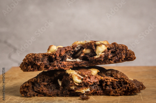 close up view of stack of the cut in half chocolate cookies with macadamia nuts and chocolate chips showing gooey texture inside and crispy edge