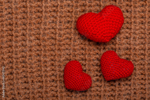 red knitted hearts on knitted background