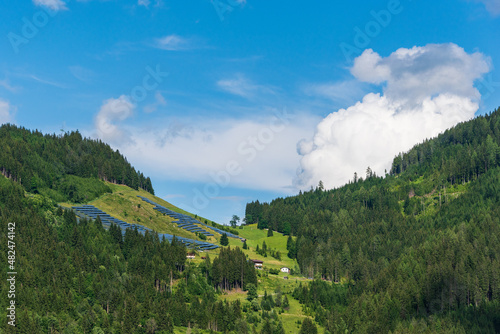 Photovoltaic, solar panels with alpine mountains in the background. Solar panels in country landscape over summer Alps is the innovation for sustainability of world solar energy.