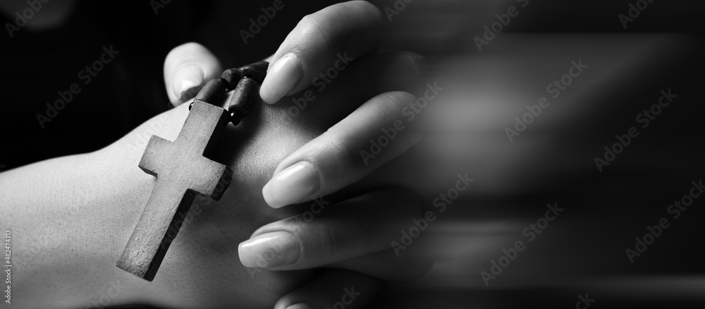 woman praying holding cross and arms crossed