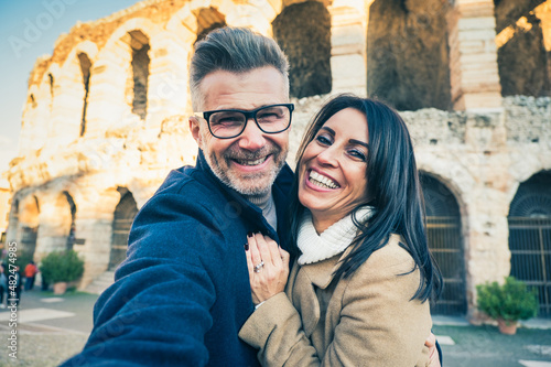 Happy couple of senior tourist having fun taking a selfie in front of famous monument of Italy - Vacation, tourism and travel concept