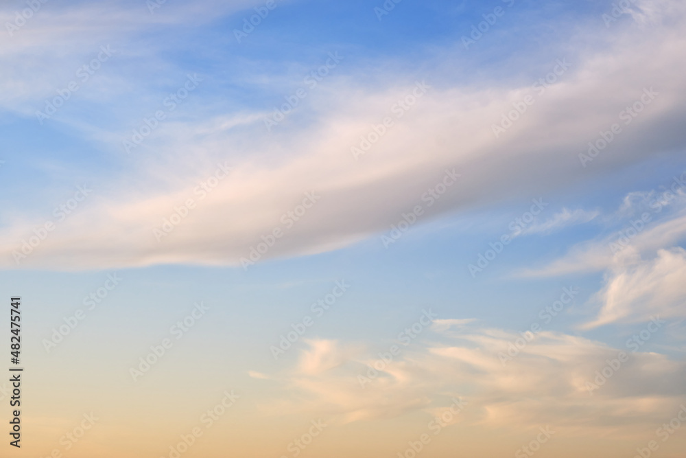 Soft fluffy clouds on the warm sunset sky, background