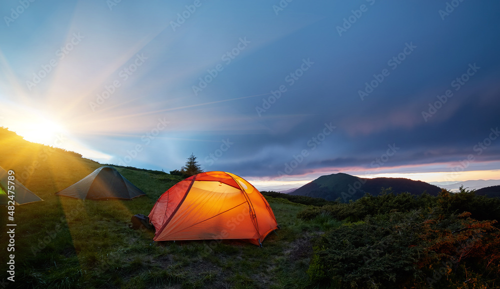 Illuminated orange camping tent under moon
