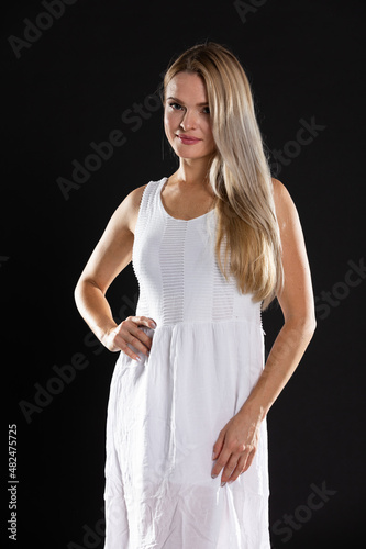 Portrait of young woman in white dress. Long hair. Black background. © fotodrobik