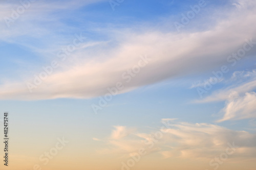Soft fluffy clouds on the warm sunset sky, background