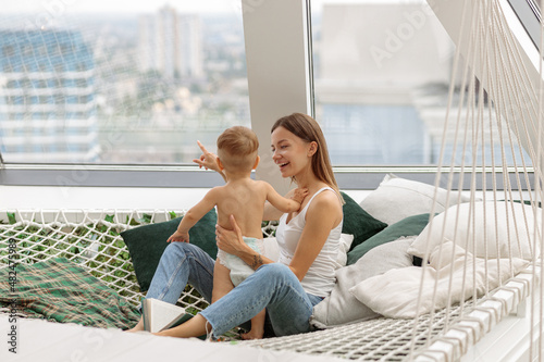 Happy young woman with her little kid sitting on mesh hammock