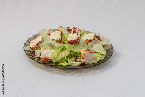 Healthy food. Iceberg lettuce with white cheese on a plate. The plate is on a white background.